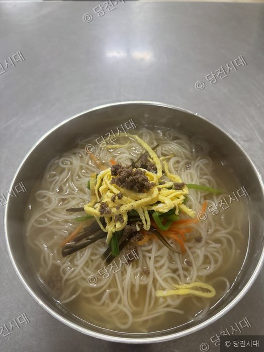 식당에서 준비된 먹음직스러운 잔치국수 한 그릇이 놓여 있다.