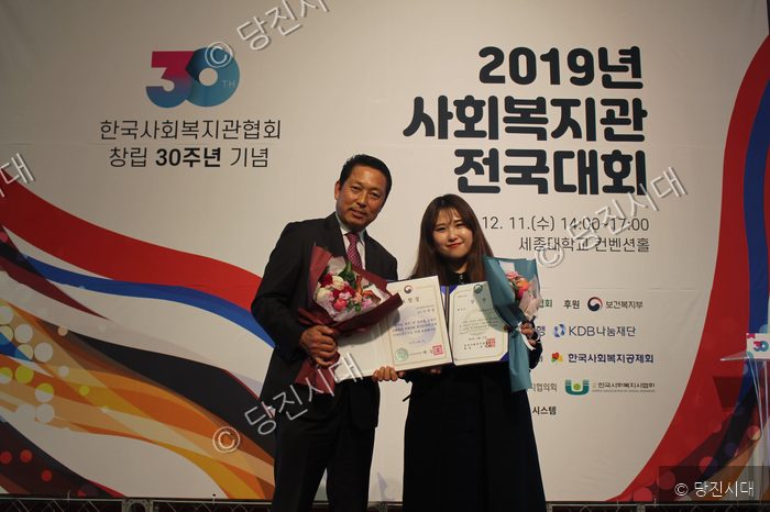 사회복지관 전국대회에서 관계자가 상장과 꽃다발을 받고 기념촬영을 하고 있다.