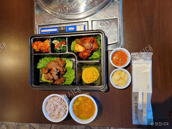 식당에서 배달 주문한 숯불구이와 반찬들이 도시락 용기에 담겨 있다.