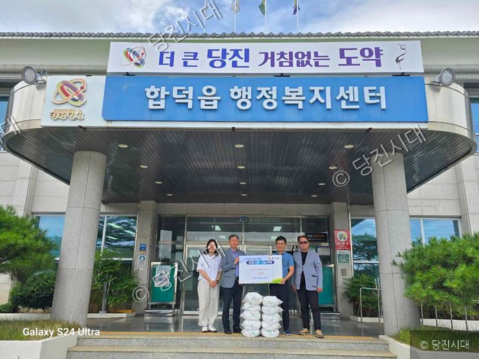 합덕읍 행정복지센터 앞에서 관계자들이 백미 기탁 기념 촬영을 하고 있다.