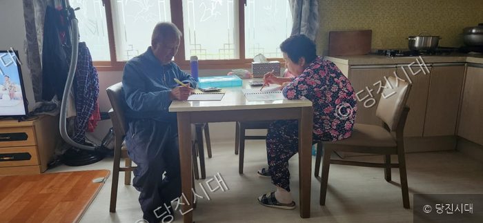 노부부가 테이블에 앉아 색칠 공부를 하고 있다.