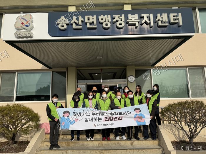 송산면행정복지센터 앞에서 시니어 건강관리 관련 현수막을 들고 기념 촬영을 하고 있다.