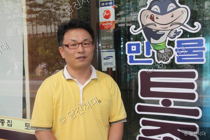신설상가 대표 신강빈이 매운탕 가게 앞에서 포즈를 취하고 있다.