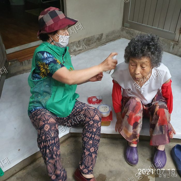 봉사자가 어르신의 몸에 소독제를 뿌려드리고 있다.