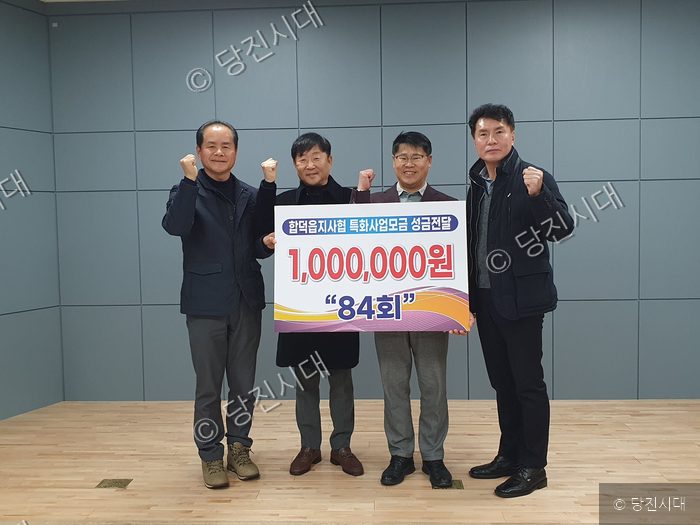 네 명의 남성이 합덕읍에 성금을 기부하고 기념 촬영을 하고 있다.