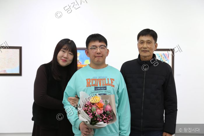 송규민 씨가 가족과 함께 미술관에서 꽃다발을 들고 기념촬영을 하고 있다.