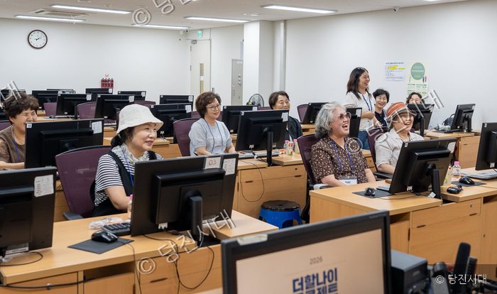 어르신들이 컴퓨터 교육 프로그램에 참여하며 밝게 웃고 있다.