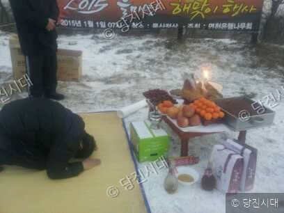 눈밭에 차려진 상 앞에서 한 사람이 절을 하고 있다.