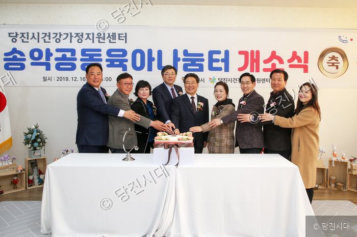참석자들이 송악공동육아나눔터 개소식 기념 케이크를 자르고 있다.