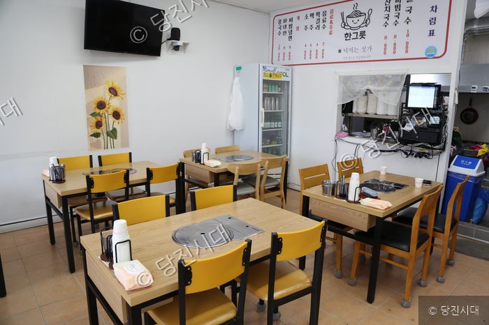 식당 내부의 테이블과 의자, 냉장고 등이 배치되어 있다.