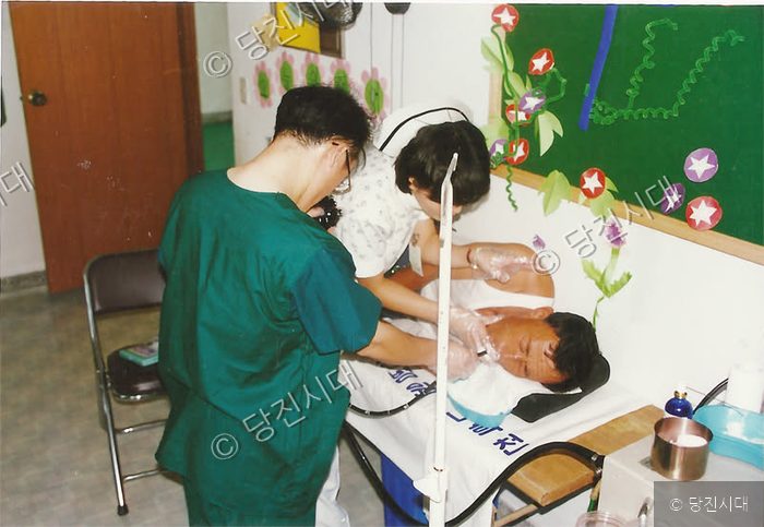 의료진이 누워 있는 환자의 상태를 진료하고 있다.
