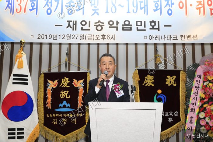 윤오석 회장이 단상에서 마이크를 잡고 행사를 진행하고 있다.