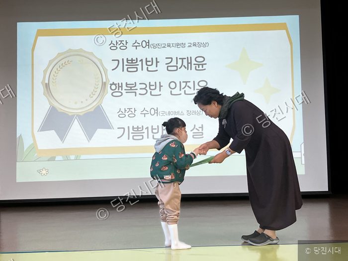 원문자 원장이 무대에서 상장을 받고 있다.