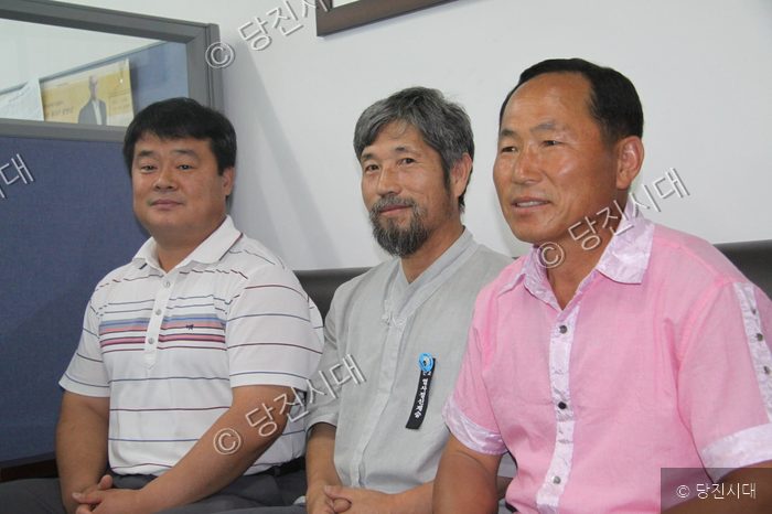 세 명의 남성이 나란히 앉아 카메라를 바라보고 있다.