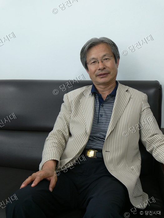 김규환 작가가 소파에 앉아 포즈를 취하고 있다.