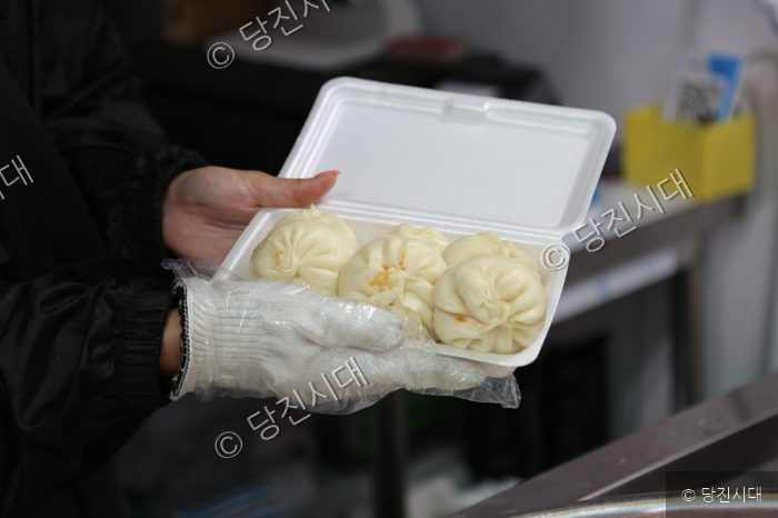 요식업 종사자가 포장 용기에 갓 찐 손만두를 담아 보이고 있다.