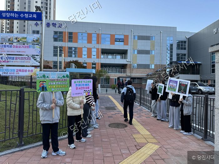 수청중학교 홍은주 교장 등이 교문 앞에서 학교폭력 예방 및 존중 캠페인을 벌이고 있다.