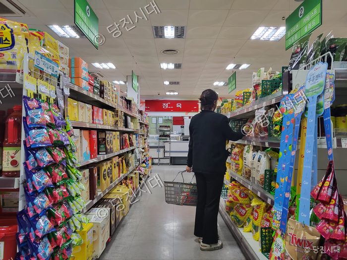마트에서 한 시민이 장바구니를 들고 물건을 고르고 있다.