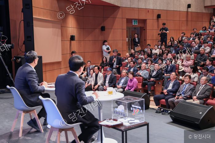 사회자와 대담자가 무대 위에서 청중과 질의응답을 진행하고 있다.