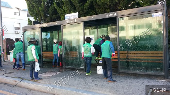 새마을회 회원들이 버스정류장을 청소하고 있다.