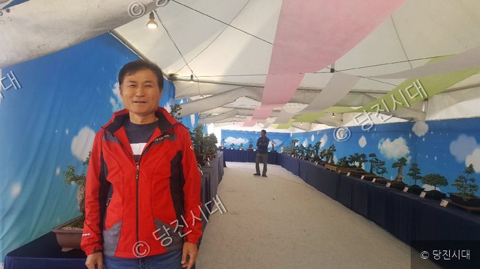 국화연구회장이 분재 전시회장에서 포즈를 취하고 있다.