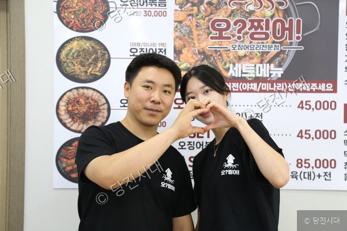 음식점 대표가 당진시 청룡길 17 메뉴판을 배경으로 포즈를 취하고 있다.