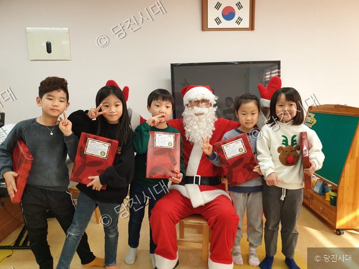산타로 분장한 인물과 어린이들이 선물을 들고 기념촬영을 하고 있다.