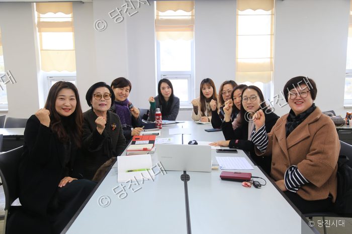여성단체 회원들이 회의실에 모여 책을 주제로 소통하며 화이팅을 외치고 있다.