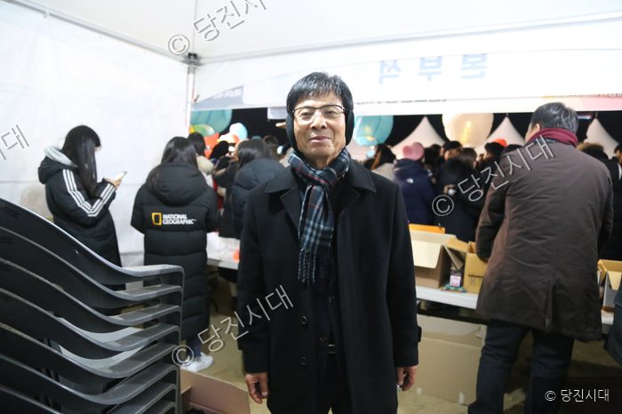 조호행 이장이 야외 행사장에서 카메라를 바라보며 서 있다.