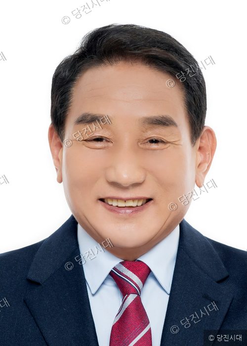 김덕주 당진시의원 후보가 정장 차림으로 미소 짓고 있다.
