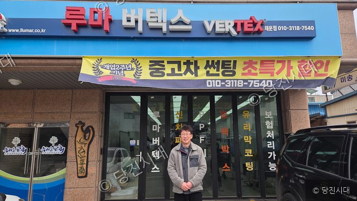 한 남성이 차량 썬팅 전문점 앞에서 포즈를 취하고 있다.