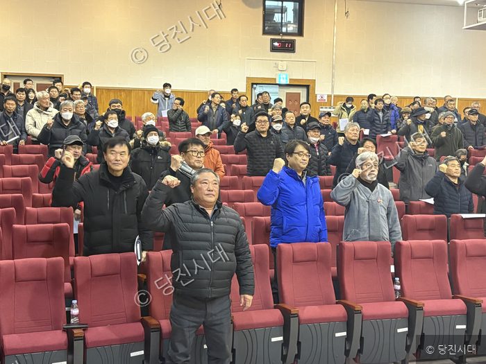당진시농민회원들이 강당에 모여 주먹을 쥐고 결의를 다지고 있다.