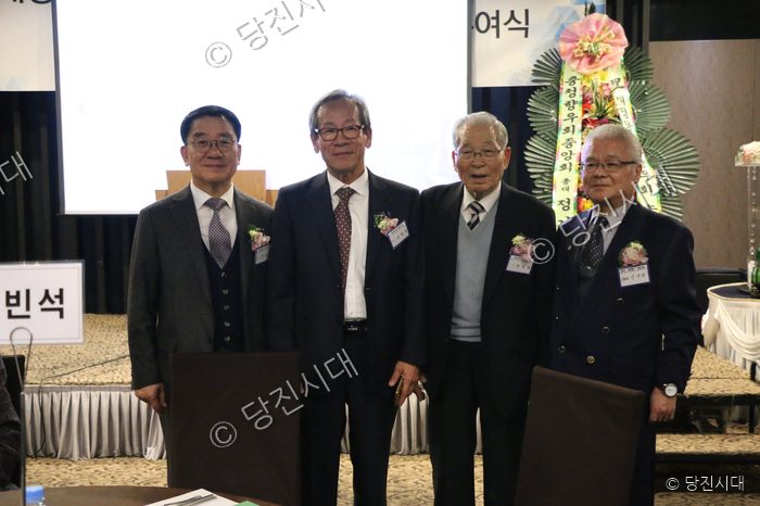 네 명의 남성이 정장 차림으로 나란히 서서 포즈를 취하고 있다.