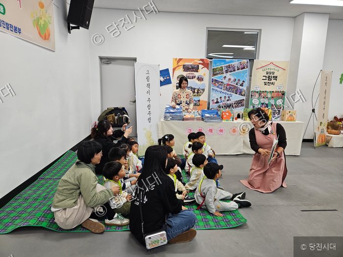 아이들과 교사들이 모여 앉아 그림책 읽기 프로그램을 즐기고 있다.