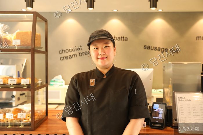 씨밀레베이커리의 최지민 대표가 매장 내부에서 미소 짓고 있다.