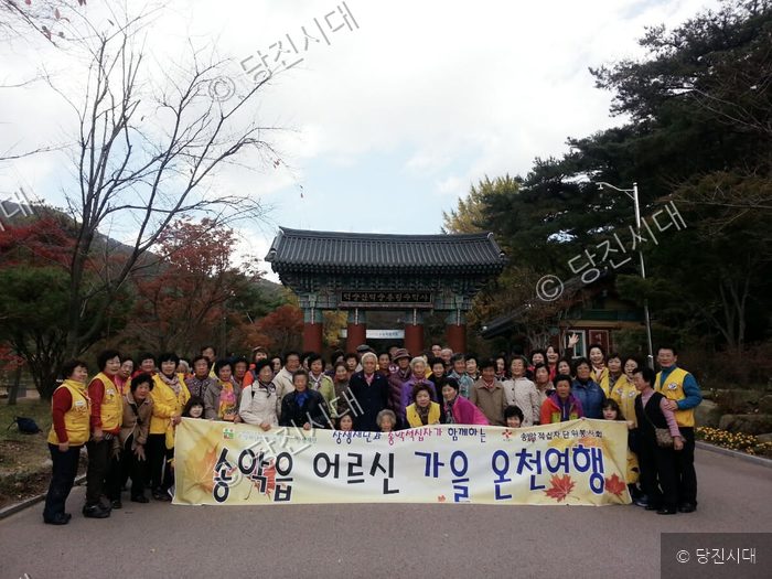 송악읍 어르신들이 단체로 가을 온천 여행을 떠나 기념 촬영을 하고 있다.