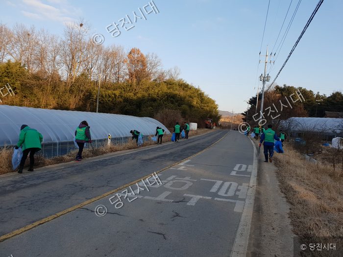 마을 주민들이 도로변에서 쓰레기를 줍는 환경미화 활동을 하고 있다.