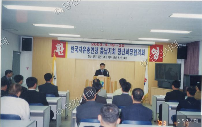 실내 강연장에서 사람들이 자리에 앉아 강연을 경청하고 있다.