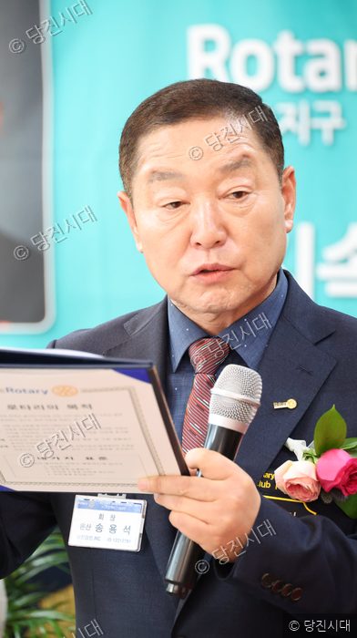한 남성이 로타리클럽 이·취임식 행사에서 마이크를 잡고 회장직을 수행하고 있다.