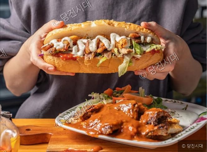 사르도르 대표가 이스탄불케밥의 대형 샌드위치를 두 손으로 들어 보이고 있다.