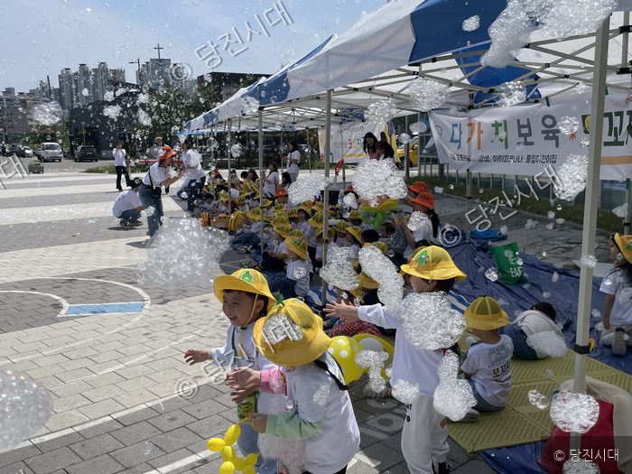 어린이들이 야외에서 버블쇼를 보며 즐거워하고 있다.