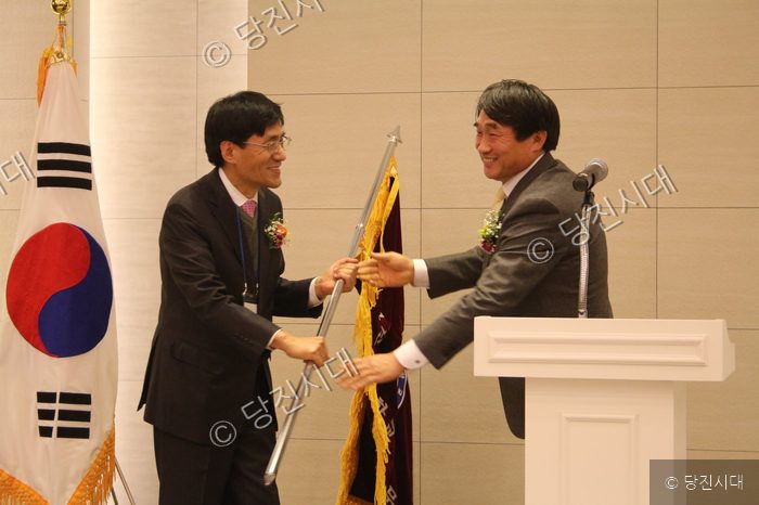 두 남자가 악수를 나누며 행사를 진행하고 있다.