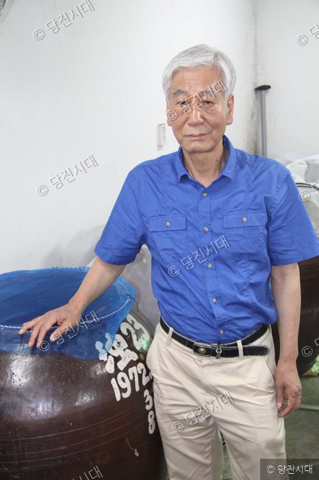 김용세 대표가 신평양조장 항아리 옆에서 포즈를 취하고 있다.