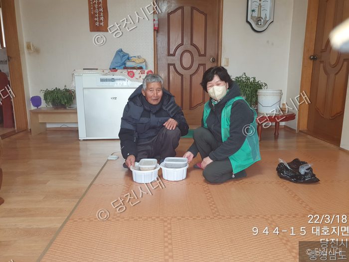 봉사자가 어르신 댁에 방문해 음식을 전달하고 있다.