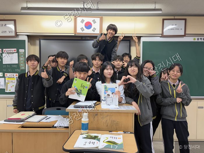 송악중학교 교실에서 교사와 학생들이 책을 들고 기념 촬영을 하고 있다.
