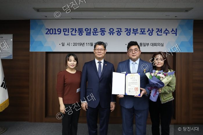 네 사람이 상장을 들고 기념 촬영을 하고 있다.