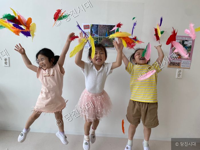아이들이 실내에서 깃털을 던지며 즐겁게 뛰어놀고 있다.