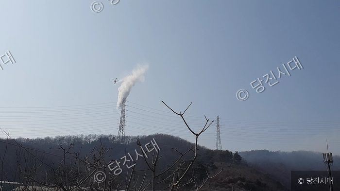 헬기가 송전탑 주변의 산불을 진화하고 있다