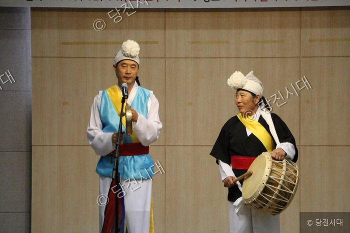 두 사람이 전통 복장을 입고 농악 공연을 하고 있다.