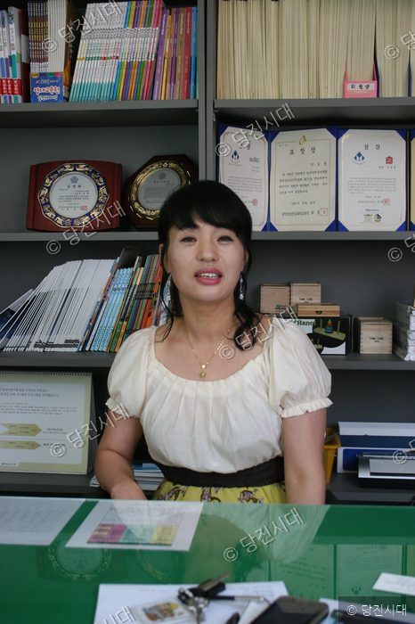 사무실 책상에 앉은 황영애 씨가 카메라를 향해 미소 짓고 있다.